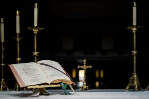 gospel-open-on-altar-with-candles-dark-church