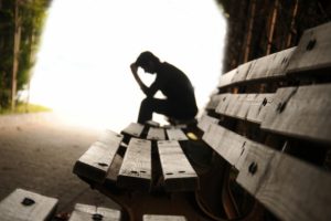 person-sitting-on-bench-with-head-in-hands