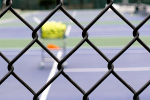 tennis-court-viewed-through-a-fence