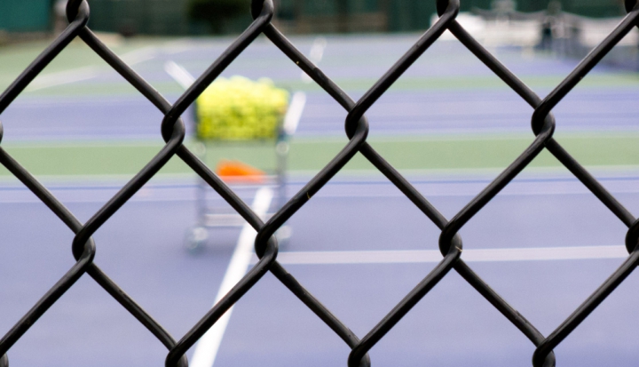 tennis-court-viewed-through-a-fence