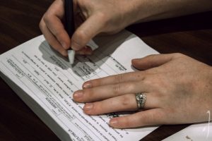 hands-signing-marriage-license