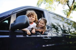 two-kids-hang-out-the-window-of-a-minivan