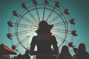 woman-stands-in-front-of-ferris-wheel