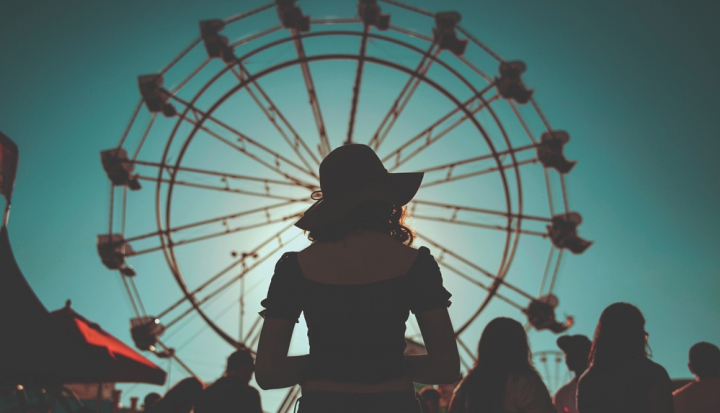 woman-stands-in-front-of-ferris-wheel