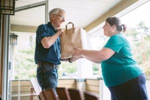 woman-gives-elderly-man-groceries