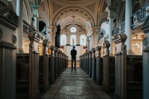 lone-figure-stands-between-pews-facing-altar