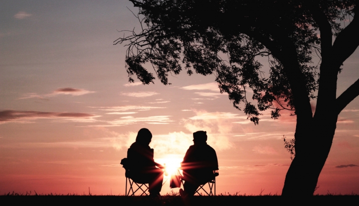 two-people-sitting-silhouetted-against-sunset