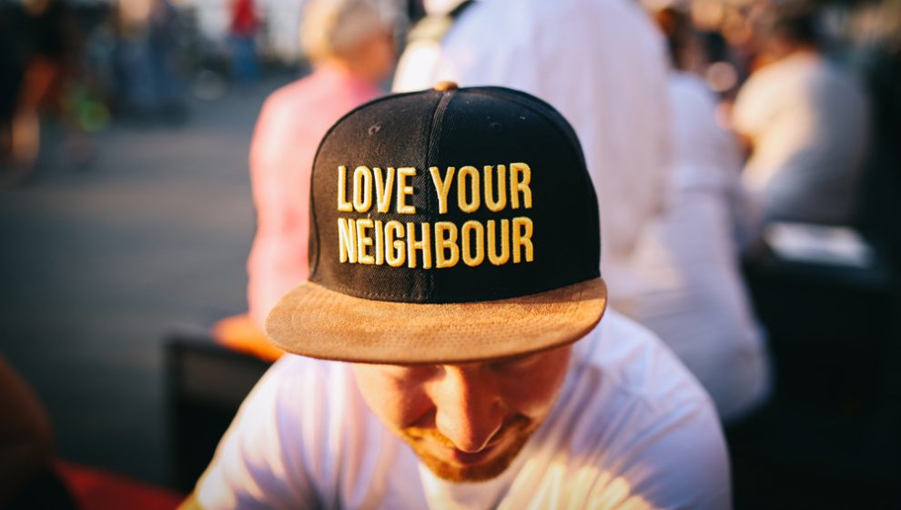 man-wearing-hat-that-says-love-your-neighbour