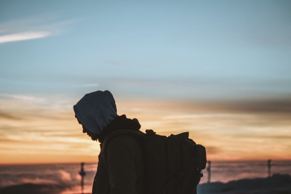 man-in-hoodie-with-backpack-looking-at-sunset