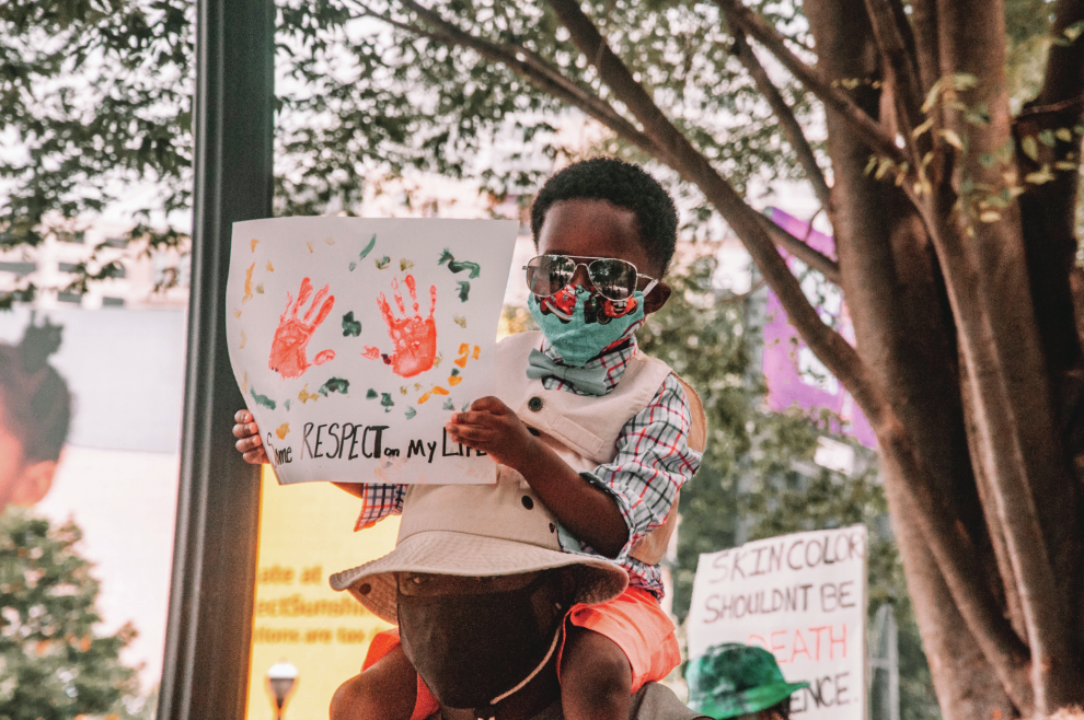 young-black-boy-sitting-on-shoulders-holding-sign