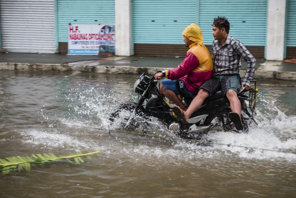 two-men-ride-a-motorcycle-through-floods-after-a-typhoon