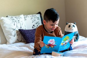 boy-reading-picture-book-in-bed