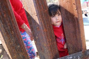 child-peeking-through-border-wall