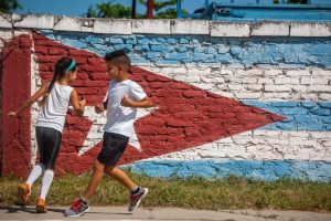 two-children-playing-in-front-of-mural-of-cuban-flag