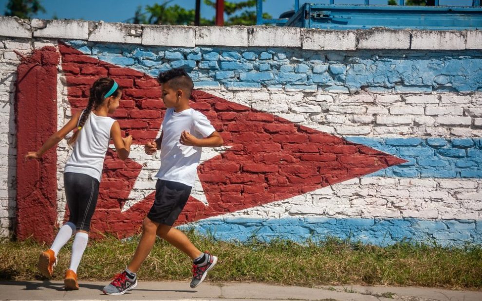 two-children-playing-in-front-of-mural-of-cuban-flag