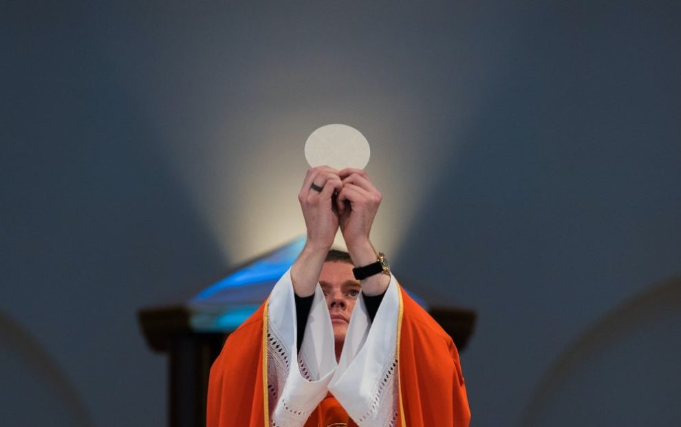 priest-holding-up-eucharist-during-mass