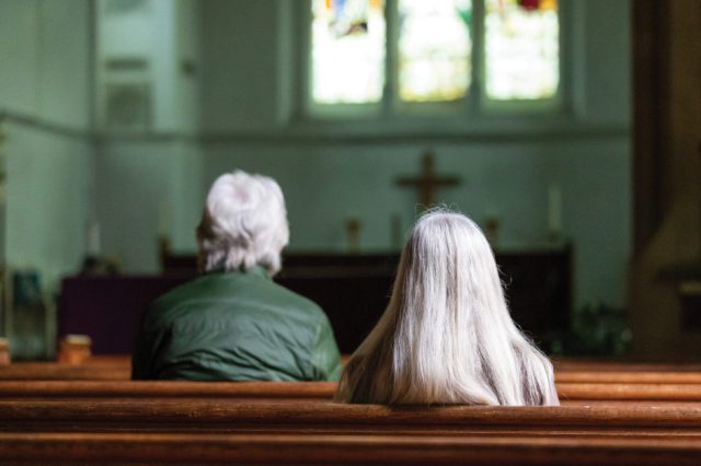 man-and-woman-with-grey-hair-sitting-in-church-pews