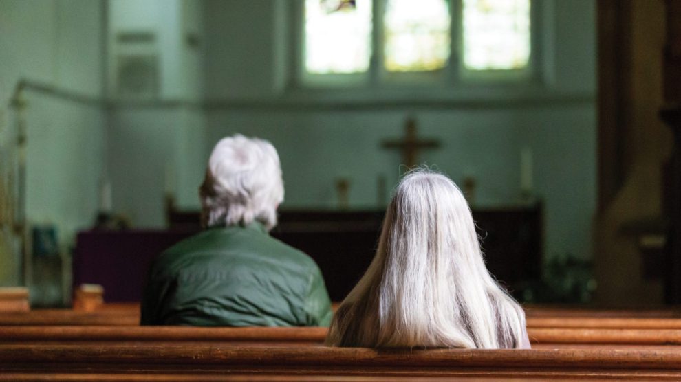 man-and-woman-with-grey-hair-sitting-in-church-pews