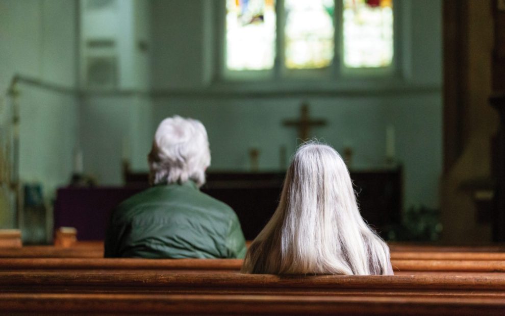 man-and-woman-with-grey-hair-sitting-in-church-pews