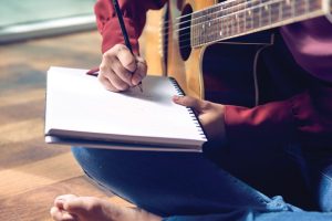 person-writing-with-guitar