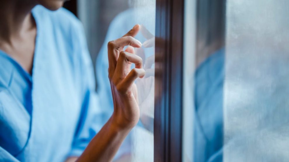 black-woman-touches-window-in-hospital