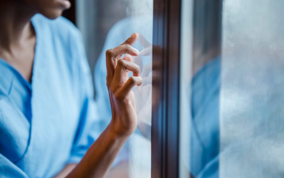 black-woman-touches-window-in-hospital