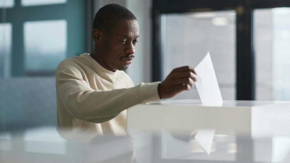 man-submitting-ballot-at-voting-booth