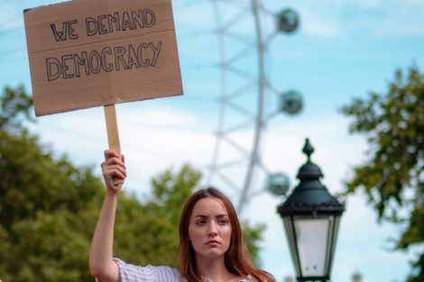 woman-holding-sign-reading-we-demand-democracy