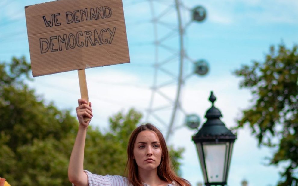 woman-holding-sign-reading-we-demand-democracy