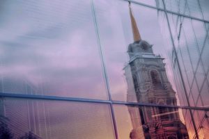 u-s-catholic-church-spire-reflected-on-glass-skyscraper