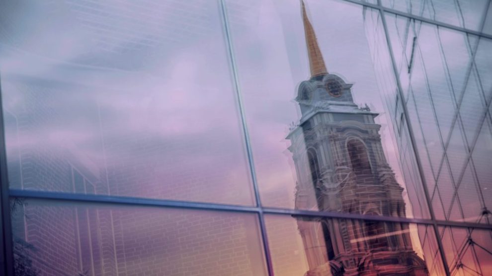 u-s-catholic-church-spire-reflected-on-glass-skyscraper