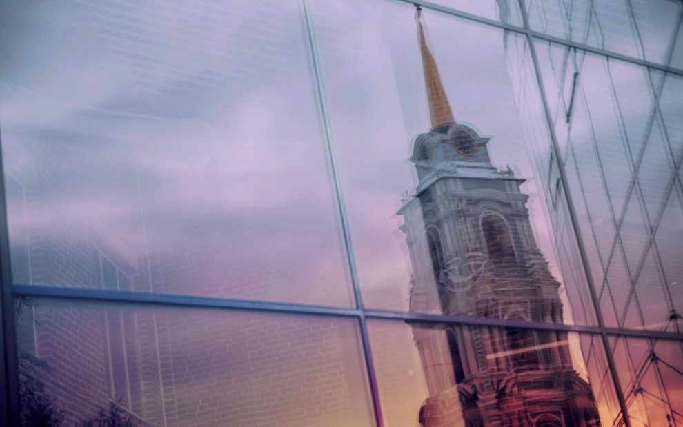 u-s-catholic-church-spire-reflected-on-glass-skyscraper