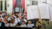 a lectern shows the Mass book while in the background you can see a congregation sitting