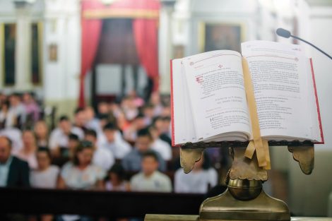 a lectern shows the Mass book while in the background you can see a congregation sitting