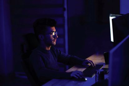 man sitting in the dark and looking at computer screen