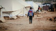 refugee child walking through a tent city