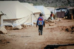 refugee child walking through a tent city