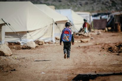 refugee child walking through a tent city