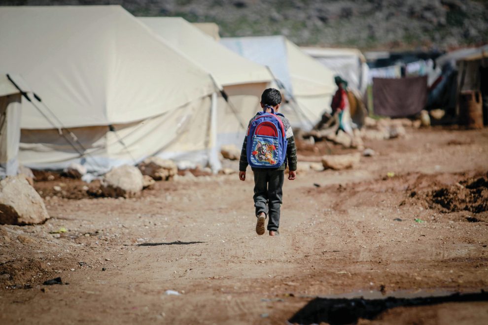 refugee child walking through a tent city