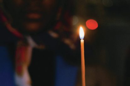 person holding a long lit candle