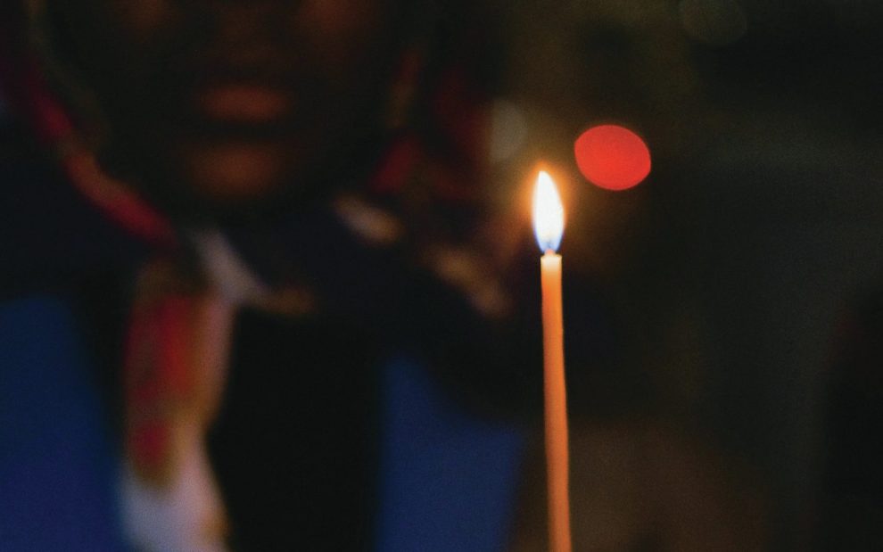 person holding a long lit candle