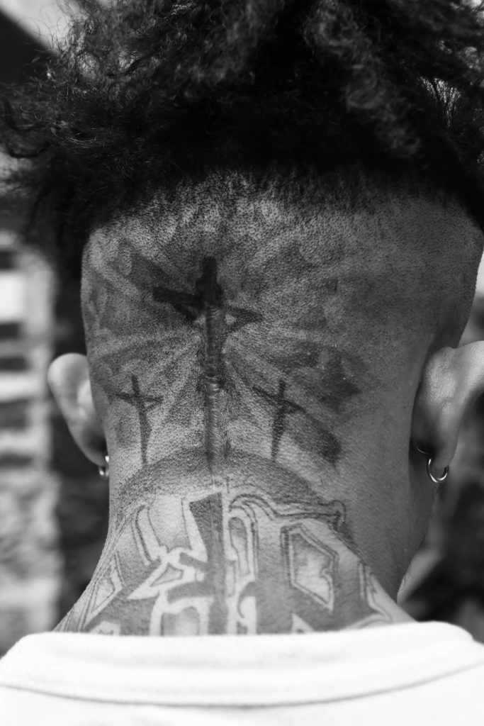 Leo has three crosses tattooed on the back of his neck, one for each family member killed or disappeared—his father and brother were murdered by members of Mara Salvatrucha and his sister is desaparecida.