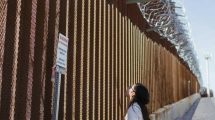 Woman looking up at border wall