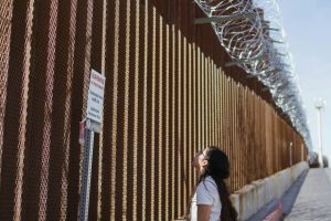Woman looking up at border wall