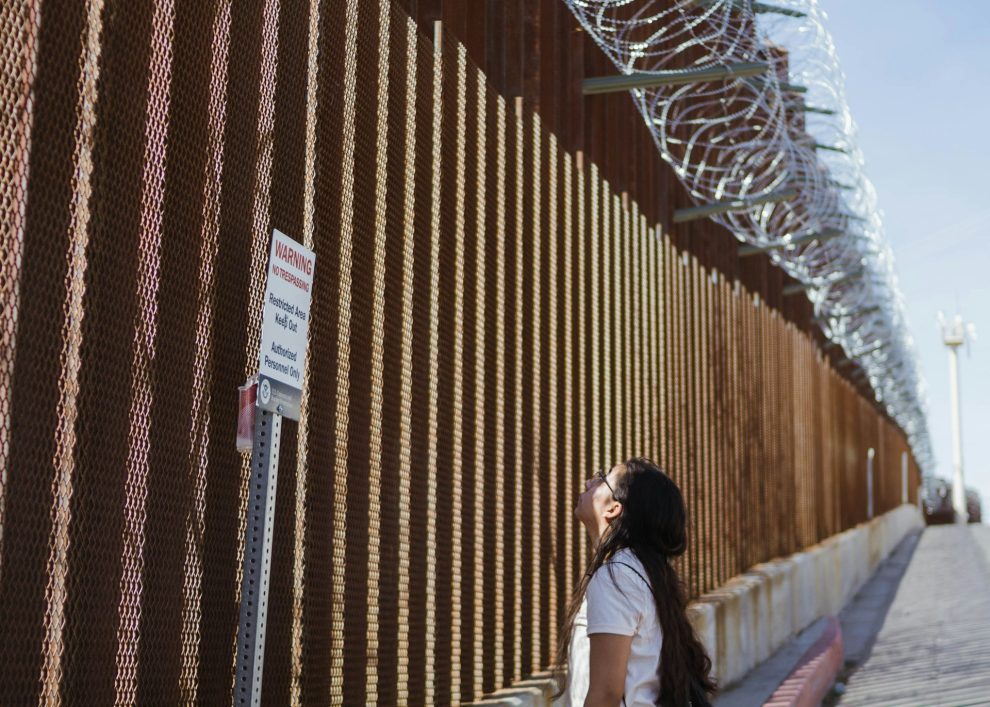 Woman looking up at border wall