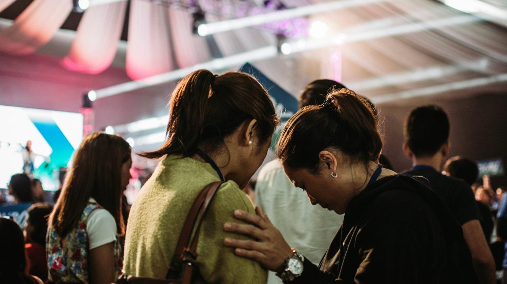 Photo of a woman touching another person's shoulder and looking down