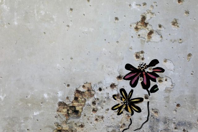 Flowers painted over bullet holes in a wall