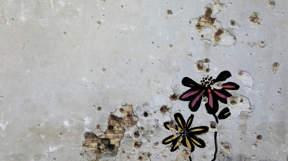 Flowers painted over bullet holes in a wall