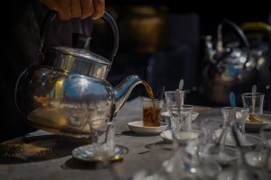 Person pouring black tea into a small glass.