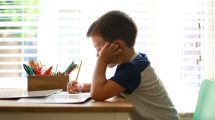 child writing in notebook with pencil